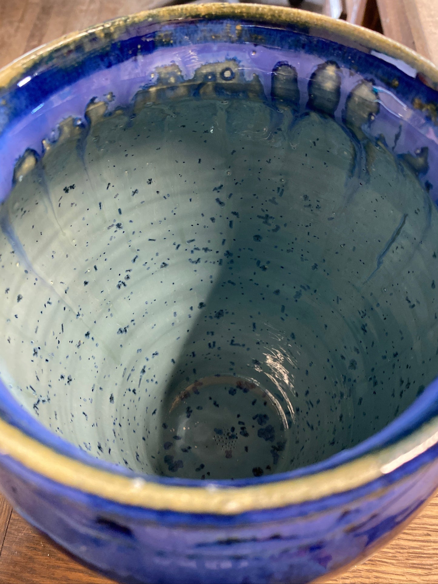 Close-up of a blue ceramic bowl with speckled interior on a wooden surface