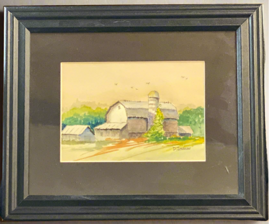 Framed watercolor painting of a barn on a gray wall