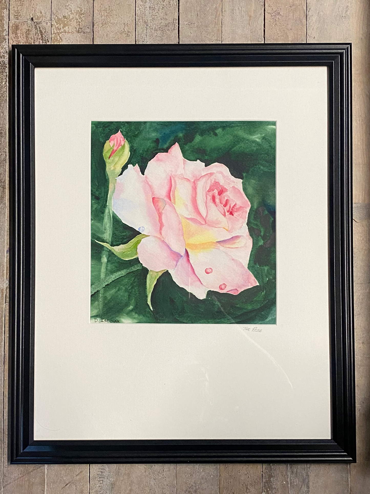 Framed artwork of a pink rose on a wooden surface
