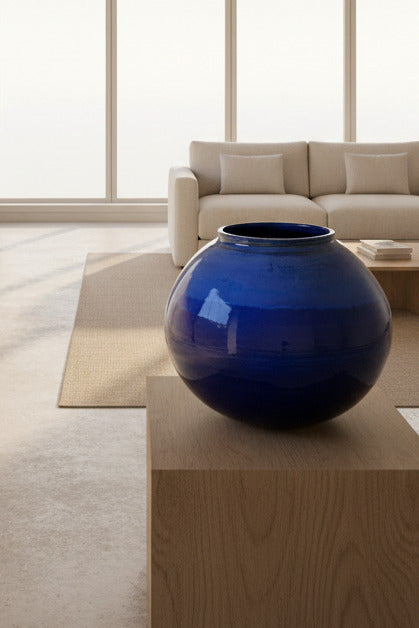 Glossy blue spherical object leaning against a wooden surface with a blurred indoor background.