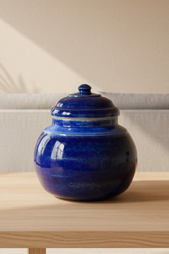Blue ceramic jar on a wooden surface with a blurred indoor background