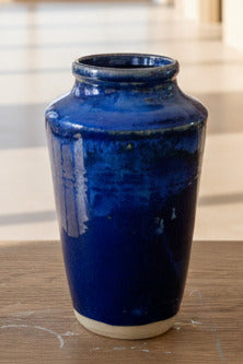 Blue ceramic vase on a wooden surface with a blurred background