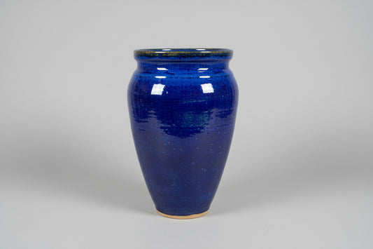 Blue ceramic mug on a wooden surface with a blurred indoor background