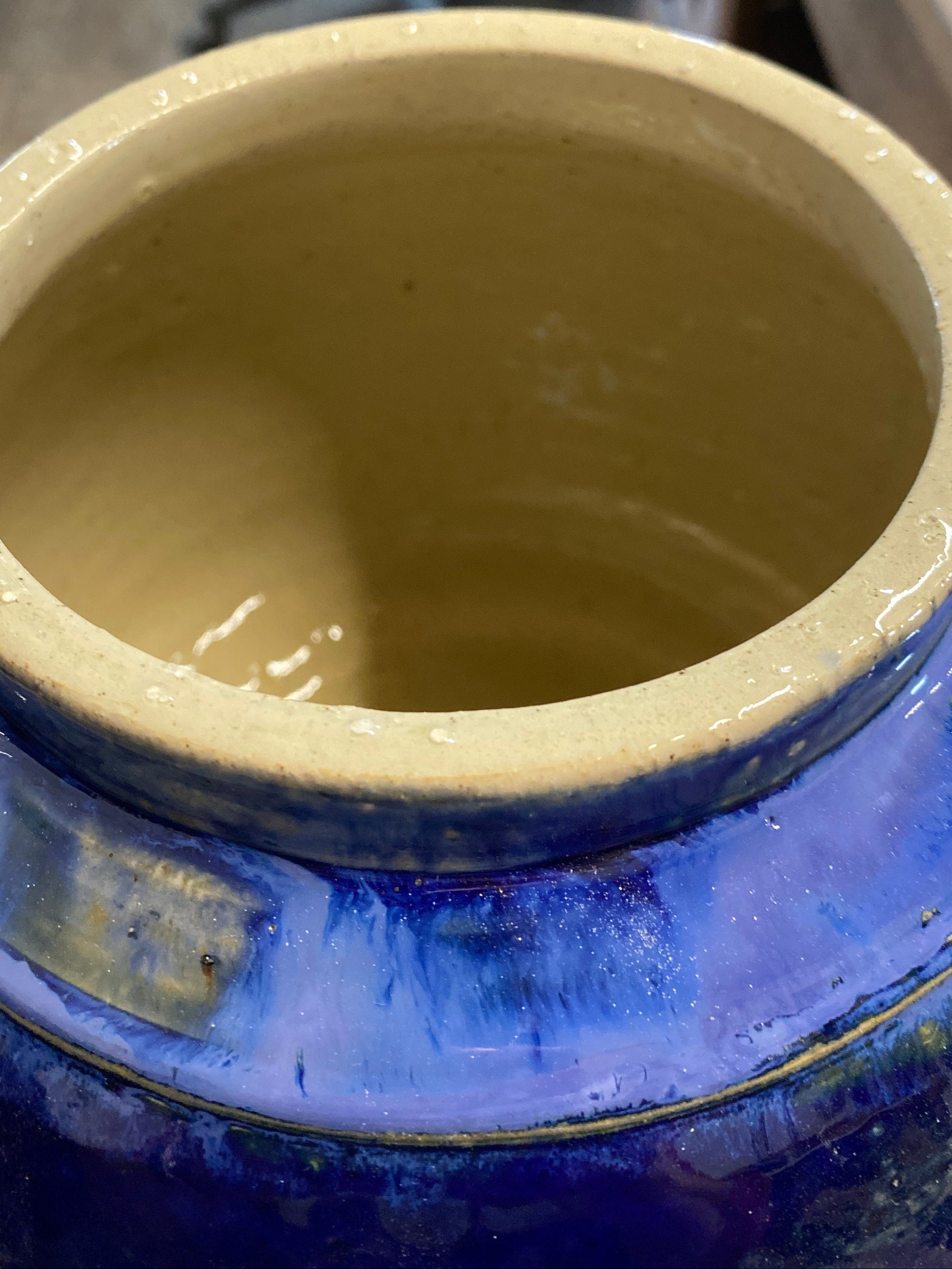 Close-up of a blue ceramic vase with a beige interior