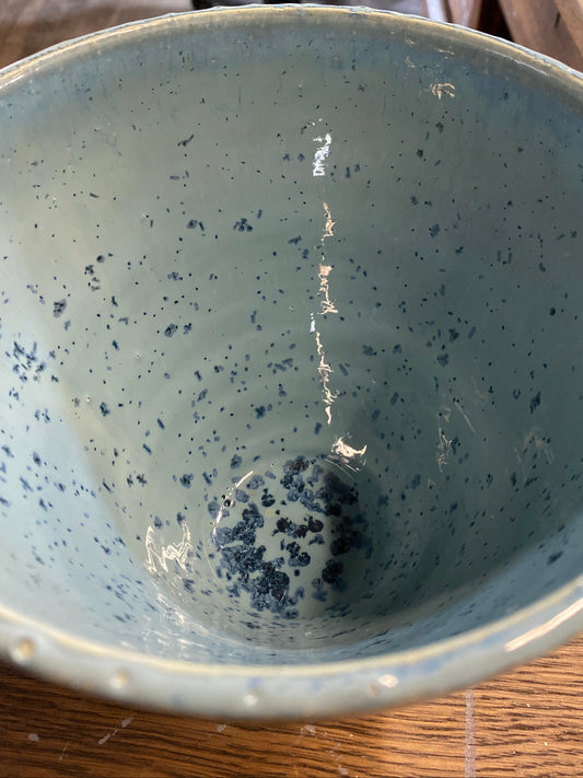 Speckled blue ceramic bowl on a wooden surface